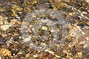 Pebble beach under clear water with waves. Pebbles underwater on the beach closeup.