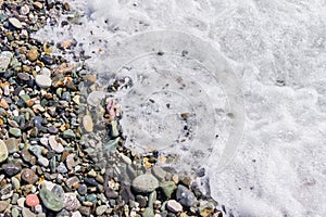 Pebble coastline. Seashore with transparent water and small stones