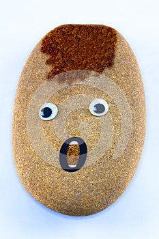 A pebble with google eyes and open mouth.