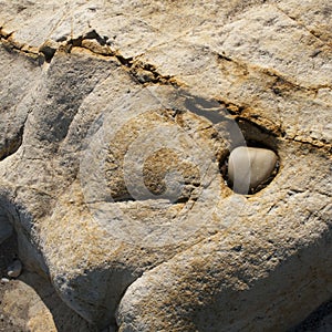 Pebble on hole in geologic rock formation on the beach, Asturias, Spain