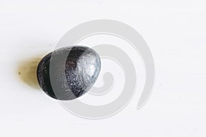 Pebble polished shungite tumbled stone on a white background with blank space