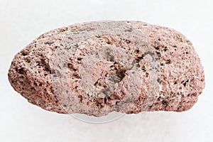 pebble of red pumice stone on white marble