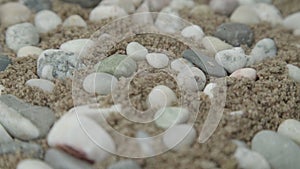 Pebble rocks of different colour and shape on blurry sand