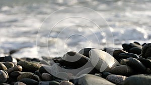 Pebble stones close up next to coming sea waves.