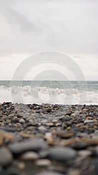 Pebble stones on the shore close up in the blurry light in the distance