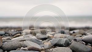 Pebble stones on the shore close up in the blurry light in the distance