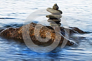 Pebble tower on rock in water.