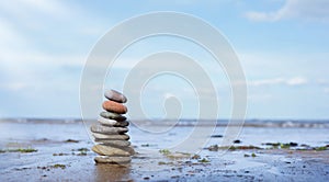 Pebble tower by seaside with blurry seascape, Stack of Zen rock stones on the sand, Stones pyramid on the beach symbolizing,