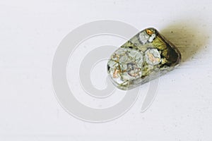 Pebble tumbled polished forest jasper stone on a white background