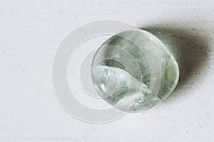 Pebble tumbled polished green fluorite stone on a white background