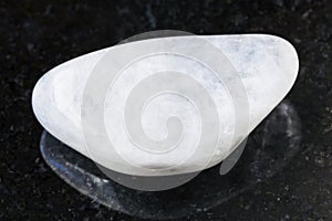 pebble of white moonstone (adularia) gem on dark