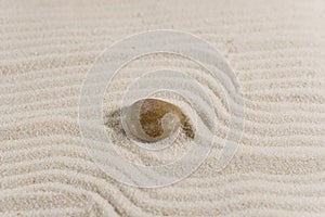 Pebble on white sand (Zen style)