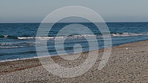 Pebbled Shoreline with Gentle Waves Under a Clear Blue Sky