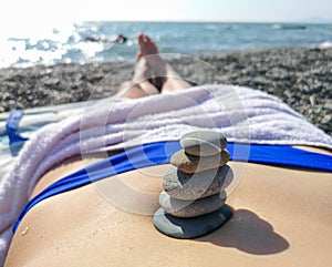 Pebbles on the body of a girl sunbathing on the beach
