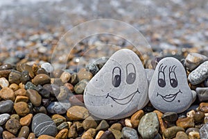 Pebbles with drawn faces in the sand. Loving couple. Travel concept.