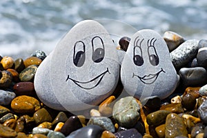 Pebbles with drawn faces in the sand. Loving couple. Travel concept.