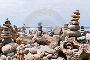 Pebbles heaped and balanced in a tower on top of mineral rocks in cityscape - Zen image of tranquility at Farol beach in Milfontes