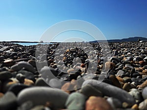 Pebbles on the sea beach close-up with blurred background of the sea. Pebble beach