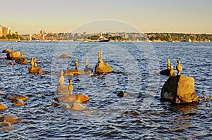 Pebbles and stones stacked on a rock seashore with seaside city in the background