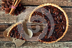 Pecan cranberry pie, overhead rustic table scene with cut slice