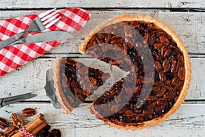 Pecan cranberry pie table scene with slice being removed photo