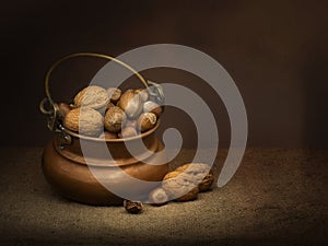 Pecan hazel and almonds - nuts in copper bowl. Chiaroscuro light painting. Vintage style dark still life. photo