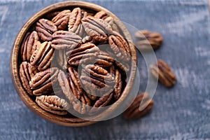 Pecan nut close-up in a round wooden cup on a black shabby board .Nuts and seeds. .Healthy fats.Heap shelled Pecans nut