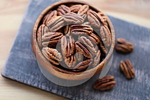 Pecan nut close-up in a round wooden cup on a black shabby board on wooden table background.Nuts and seeds. .Healthy