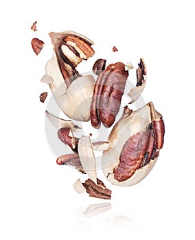 Pecan nuts crushed into pieces, frozen in the air on a white background