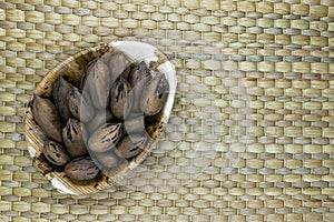 Pecan Nuts with the Nutshell in Eco Natural Banana Leaf Plate on Natural Bamboo Mat Surface with Free Space