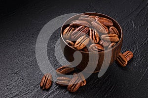 Pecan nuts in wooden bowl on black background