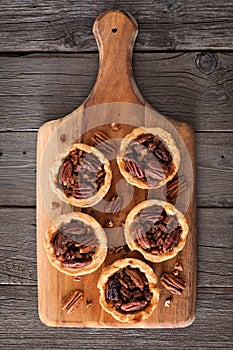 Pecan pie tarts on a wooden paddle board