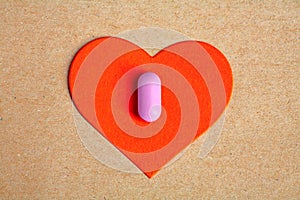 Ped paper heart shape over craft paper with one small pink pill on.