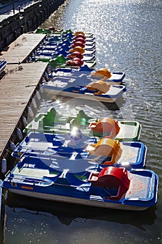 Pedal boat in a row near pier with sun flares