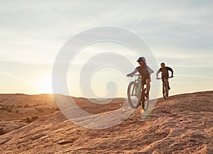 Pedalling it out. Full length shot of two young male athletes mountain biking in the wilderness.