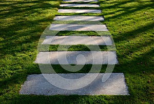 Concrete path lawn pedal rectangular shape in regular grid routed directly through beautiful lawn suns and shadows stone photo