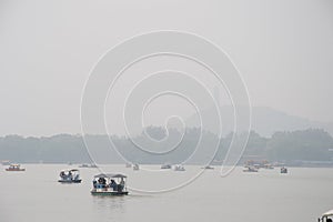 Peddle boats in haze on lake in China