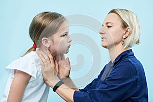 Pedeatrician female doctor making throat palpation of little girl photo