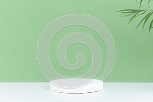 Pedestal podium on a white table, green background with palm tree leaves