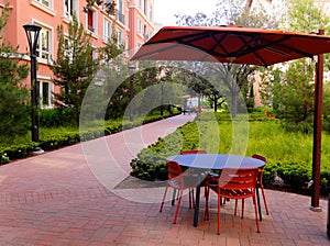 Pedestrian alley red umbrellas outdoor table and chairs in a new apartment complex