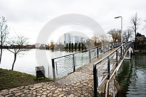 Pedestrian bridge of lake promenade with glass building multistorey residental house on background