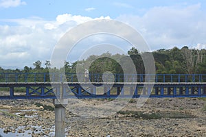 Pedestrian bridge over rock rivers, trees, and cloudy sky photo