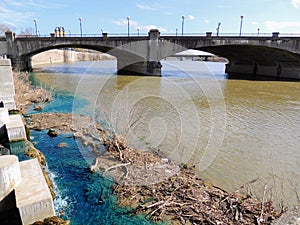 Pedestrian bridge in White River State Park Indianapolis Indiana with muddy and vivid blue water mixing