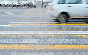 Pedestrian crossing, car driving at fast speed blurred motion, outdoors in winter.
