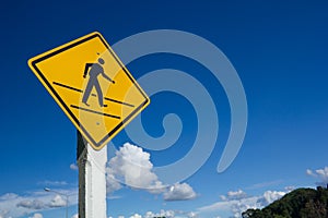 Pedestrian crossing road sign against blue sky.