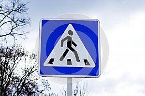 Pedestrian crossing road sign on sky background with clouds