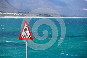 Pedestrian crossing sign and blue ocean in the background