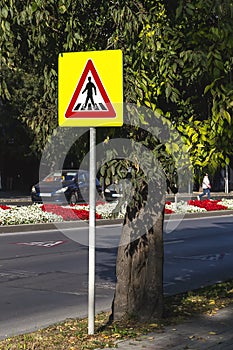 The pedestrian crossing sign on a bright yellow background made of a reflective fluorescent film for better visibility. Traffic