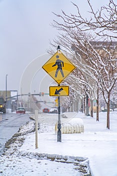 Pedestrian Crossing sign on a snowy sidewalk