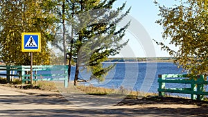 A pedestrian crossing sign stands by the trees next to the cliff.